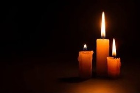 3 burning memorial candles against a black background